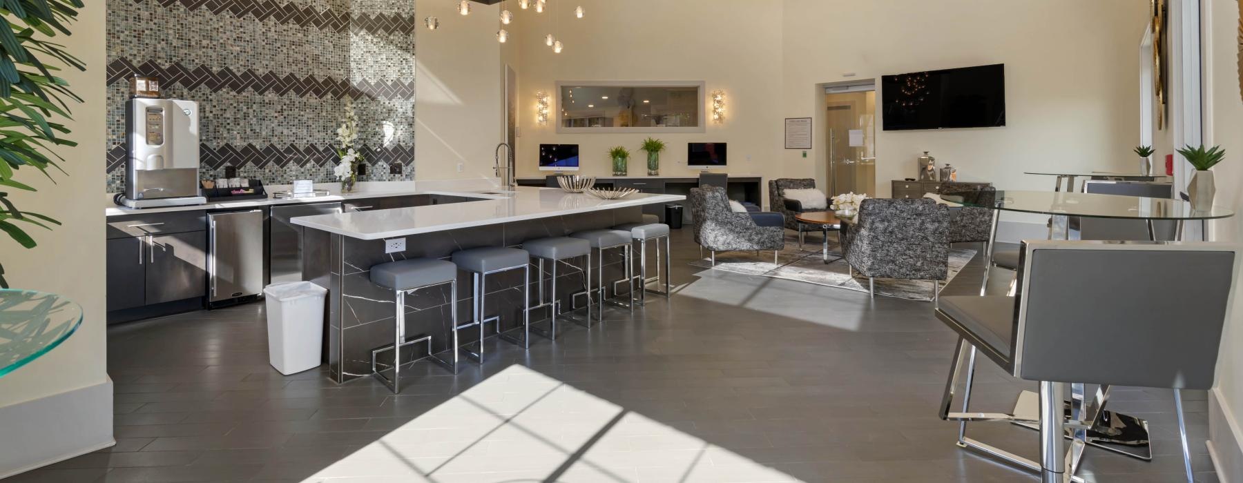 a large kitchen with a bar and chairs in clubhouse